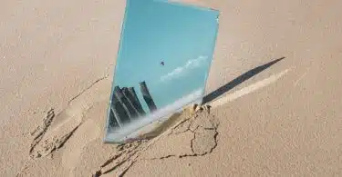 a reflection of a building in a mirror on a beach
