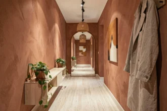 Couloir étroit décoré en style contemporain 2026 avec murs en plâtre terracotta, console en chêne blanc et grand miroir arqué