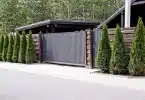 portail gris en aluminium sur une entrée de maison avec des sapins