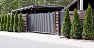 portail gris en aluminium sur une entrée de maison avec des sapins